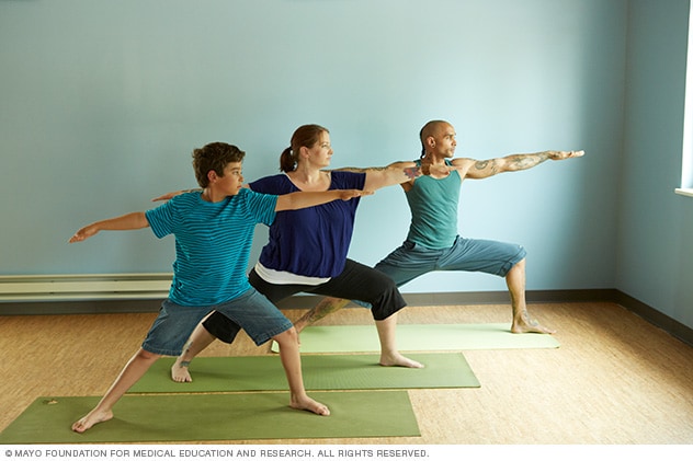 Three people performing a yoga pose while standing